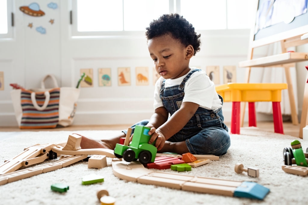 Cute little boy playing with a railroad train toy